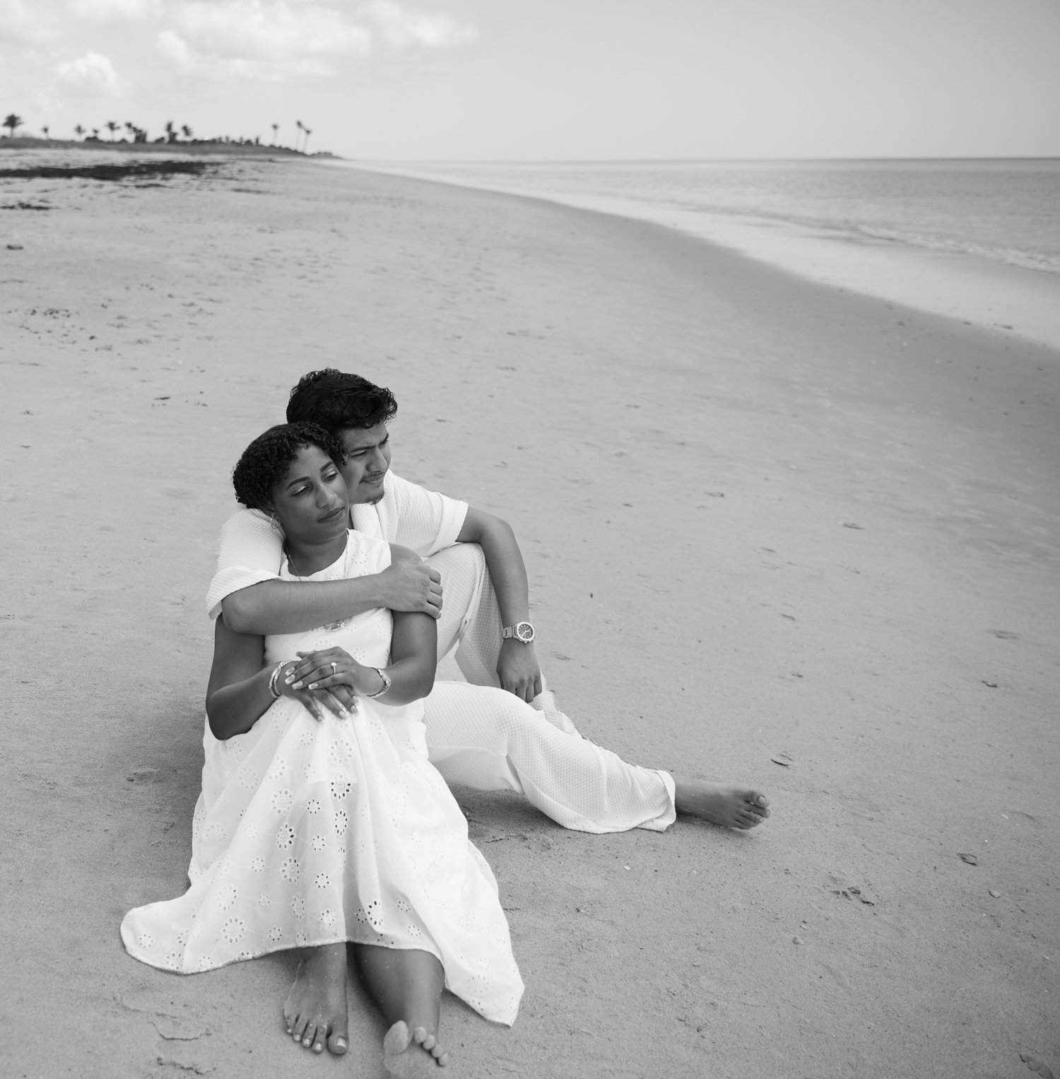 Black and white portrait of Josue and Yassiel seated together on the beach